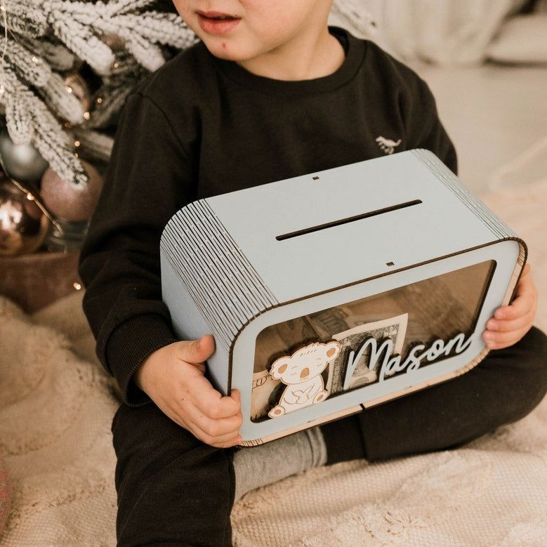Child holding the real wooden savings bank for scale
